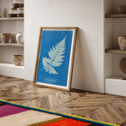 Botanical cyanotype artwork of a fern by Anna Atkins titled Lastrea Spinulosa A framed poster of a botanical illustration titled Lastrea Spinulosa by Anna Atkins showing a detailed fern leaf on a deep blue background.