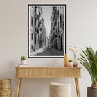 Schwarzweißfotografie von Street of Barcelona, die einen Mann zeigt, der eine schmale Stadtstraße entlanggeht. Schwarzweißposter mit der Abbildung einer schmalen Straße in Barcelona mit dem Titel „Straße von Barcelona“ und einer Person in der Mitte.