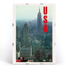 Skyline view of New York with bold USA letters in artwork by U.S. Information Agency USA New York Department of Commerce Poster titled New York by U.S. Information Agency depicting a cityscape view with skyscrapers and large red letters USA.
