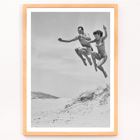 Acrobatic jump at the beach by Tivoli stars Acrobatics at the Beach Poster of Acrobatics at the Beach by Two Tivoli Stars featuring two people in swimsuits jumping on a sandy beach.