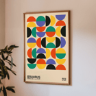 Colorful geometric shapes in Bauhaus Poster 11 inspired by the Weimar Exhibition. Bauhaus Poster 11 features colorful geometric shapes in a grid pattern inspired by the Weimar Exhibition artwork.