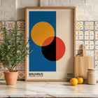 Bauhaus Póster 17 diseño geométrico abstracto del artista Bauhaus Bauhaus Póster 17 presenta círculos entrecruzados en naranja, rojo, negro sobre fondo azul y beige enmarcados con texto en la parte inferior.