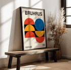Bauhaus Póster 18 con formas geométricas en rojo, azul y amarillo sobre un fondo blanco Bauhaus Póster 18 presenta formas geométricas audaces y colores primarios en un diseño minimalista con el texto Bauhaus en la parte superior.