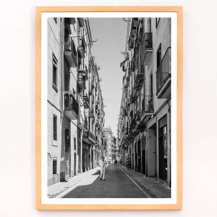Schwarzweißfotografie von Street of Barcelona, die einen Mann zeigt, der eine schmale Stadtstraße entlanggeht. Schwarzweißposter mit der Abbildung einer schmalen Straße in Barcelona mit dem Titel „Straße von Barcelona“ und einer Person in der Mitte.