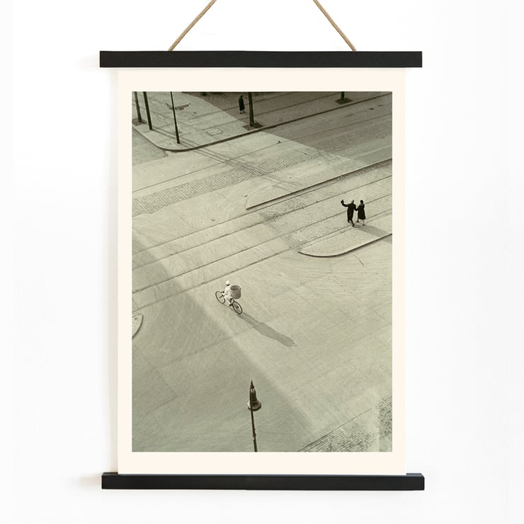 Cyclist on an empty street at dawn captured in artwork 7 AM New Years Morning by László Moholy-Nagy Poster of a black and white city street scene with a cyclist by László Moholy-Nagy titled 7 A.M. New Year’s Morning