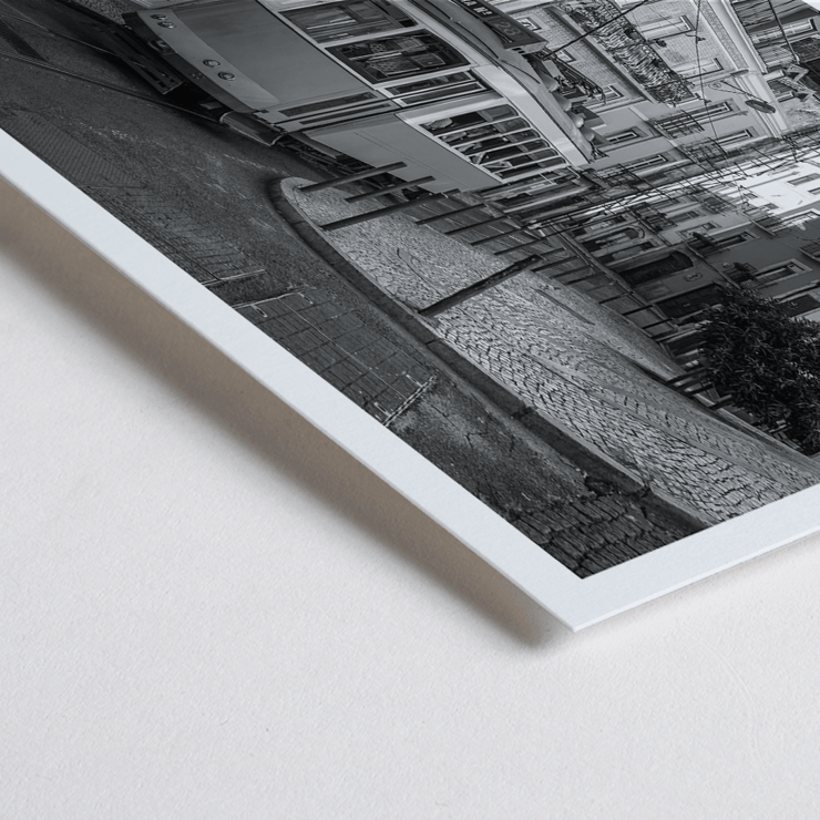 Lisbon Tramway 28 by Black & White Picture showing historic tram in Lisbon street scene Poster featuring Lisbon Tramway 28 Black & White Picture showing the tram navigating through narrow, historic streets with cobblestone pathways.