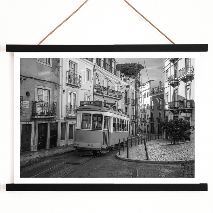 Lisbon Tramway 28 by Black & White Picture showing historic tram in Lisbon street scene Poster featuring Lisbon Tramway 28 Black & White Picture showing the tram navigating through narrow, historic streets with cobblestone pathways.