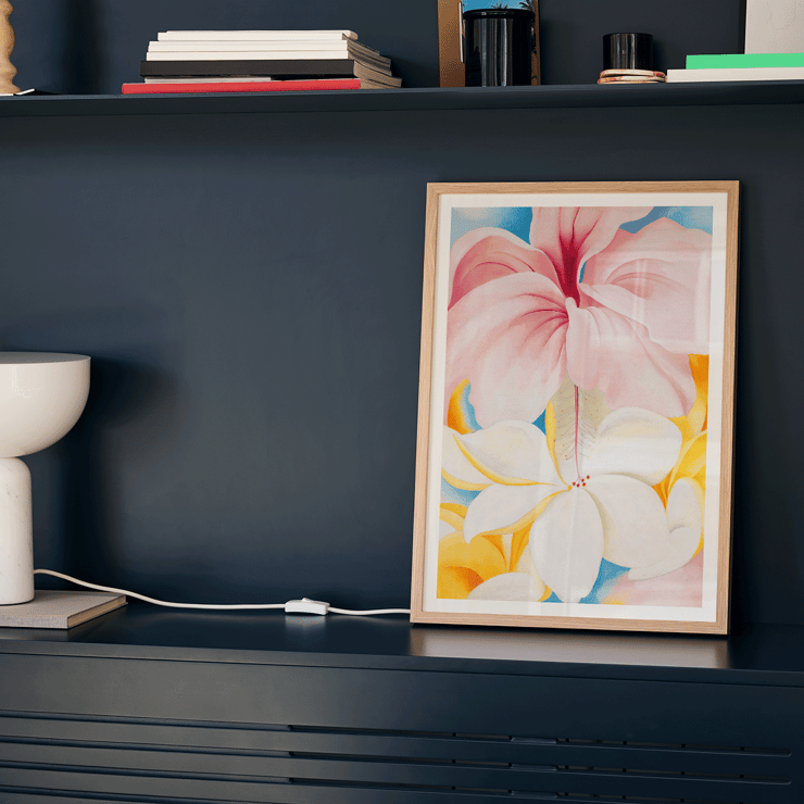 Hibiscus with Plumeria by Georgia O'Keeffe features large vibrant flowers in a colorful composition. Poster of Hibiscus with Plumeria by Georgia O’Keeffe featuring vibrant pink and white flowers with a colorful background