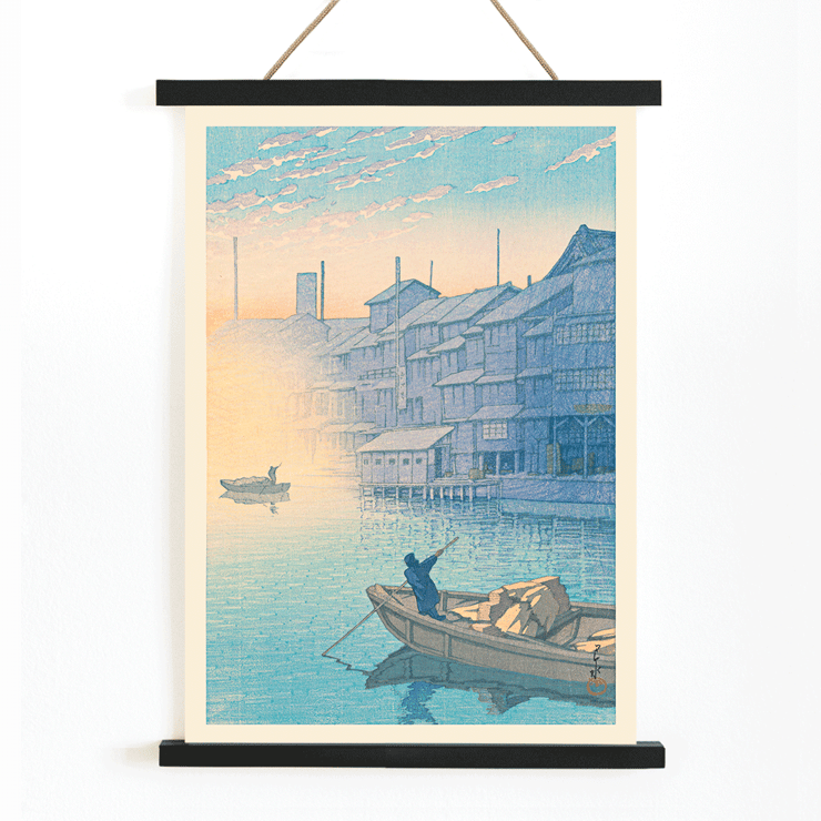 Paisagem matinal com barcos e casas na água por Kawase Hasui Manhã em Dotonbori Pôster de Manhã em Dotonbori, de Kawase Hasui, mostrando uma cena serena de rio com barcos e casas de madeira ao amanhecer.