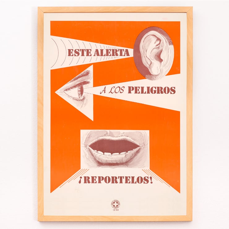 Esta alarma a los peligros Reportelos von zeigt Ohr-, Augen- und Mundsymbole in einem Sicherheitsplakat Poster mit dem Titel „Esta alerta a los peligros Reportelos“ mit einem Ohr, Auge und Mund in einem kräftigen orange-weißen Design