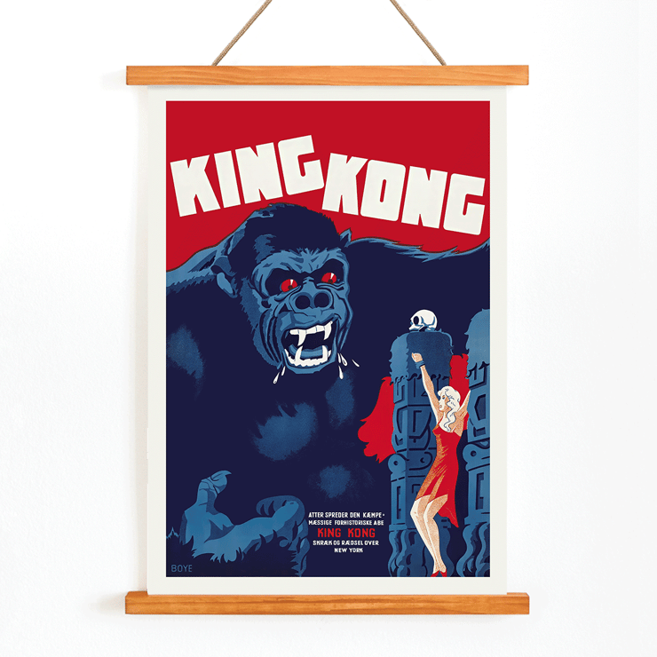 Póster de la película King Kong de Boye que presenta una escena icónica con un mono gigante y una mujer. Afiche de la película King Kong de Boye que muestra a un gorila gigante con ojos rojos agarrando un edificio con una mujer con un vestido rojo levantando su mano.