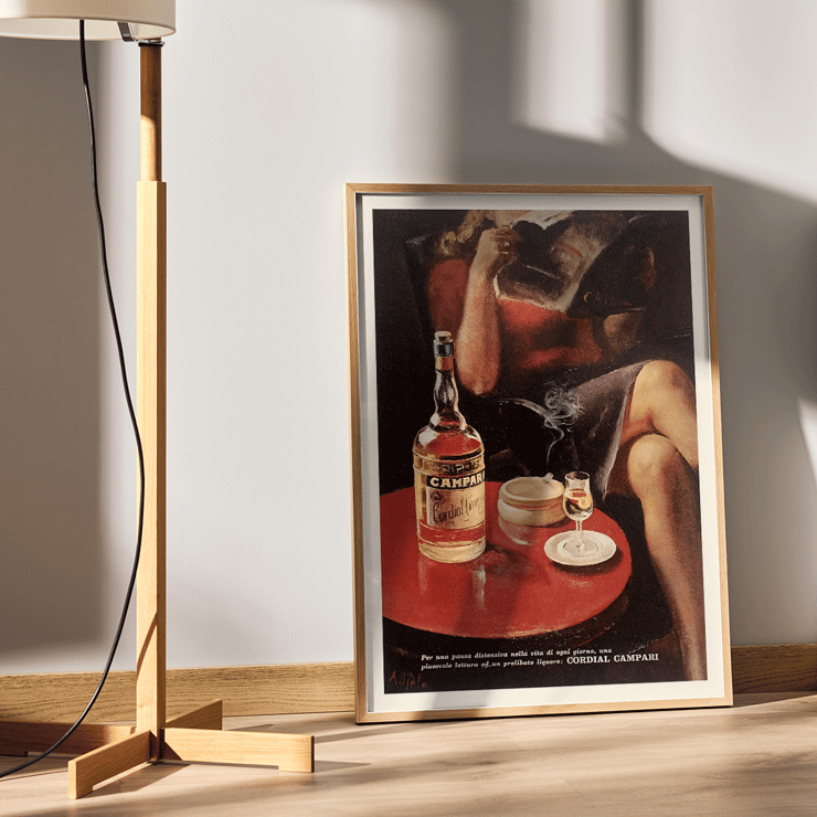 Cordial Campari Vintage poster by artist Miroglio featuring a woman relaxing with a drink and magazine. Cordial Campari Vintage poster by Nizzoli featuring a seated woman with a magazine and a bottle on a table.