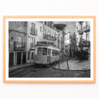 Póster con el tranvía 28 de Lisboa Imagen en blanco y negro que muestra el tranvía circulando por calles estrechas e históricas con caminos adoquinados.