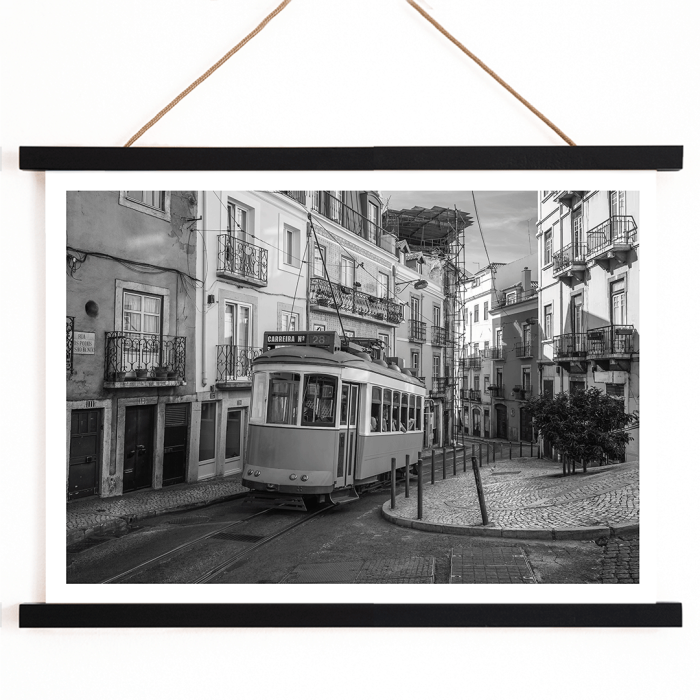 Póster con el tranvía 28 de Lisboa Imagen en blanco y negro que muestra el tranvía circulando por calles estrechas e históricas con caminos adoquinados.