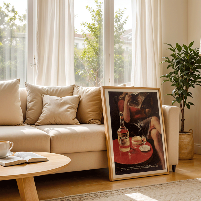 Póster vintage Cordial Campari de Nizzoli que muestra una mujer sentada con una revista y una botella sobre una mesa.